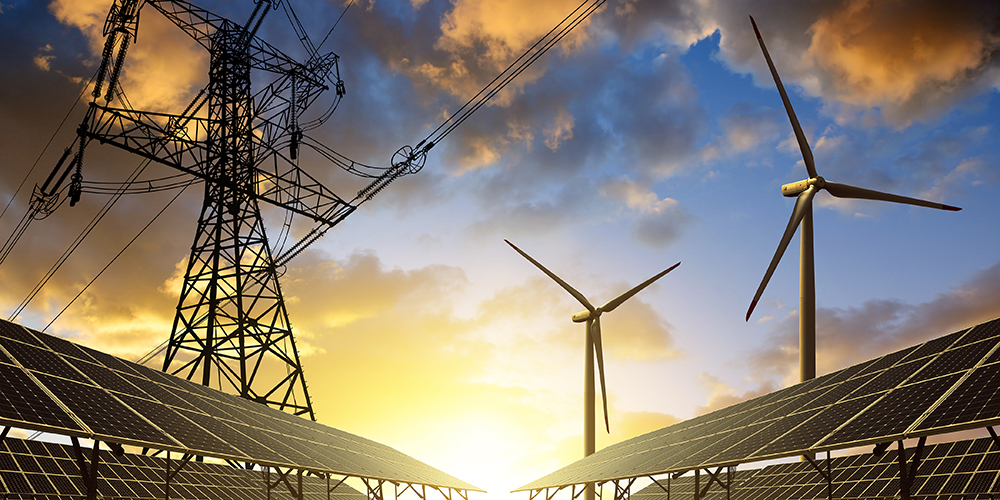 solar panels, wind turbines, and an electricity transmission tower in front of the sun rising into a blue sky with puffy clouds
