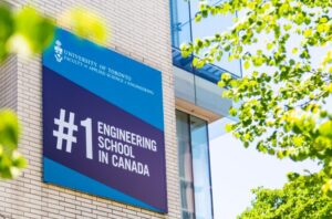 Photo of a banner on the exterior of the Bahen Centre. The banner is dark blue and cyan with the Faculty's crest and the words "#1 Engineering School in Canada" in white text.
