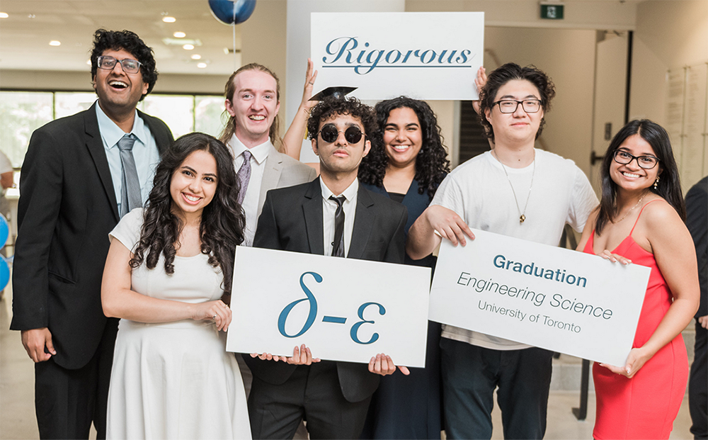 a group of male and female graduates holding up photo booth signs during EngSci's Convocation Reception