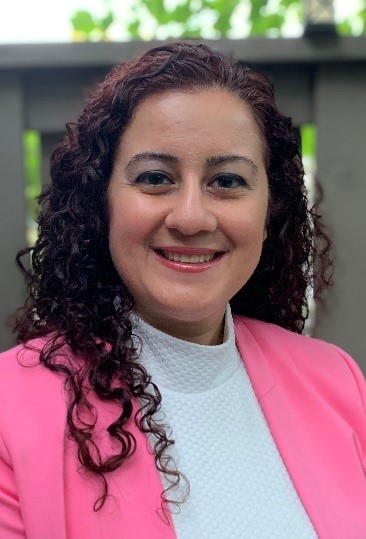 photo of Alis Ekmekci smiling and wearing a bright pink jacket over a white hirt