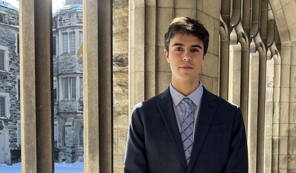photo of Gonzalo Martinez Santos wearing a suit and tie and standing next to arched windows in one of U of T's historic buildings