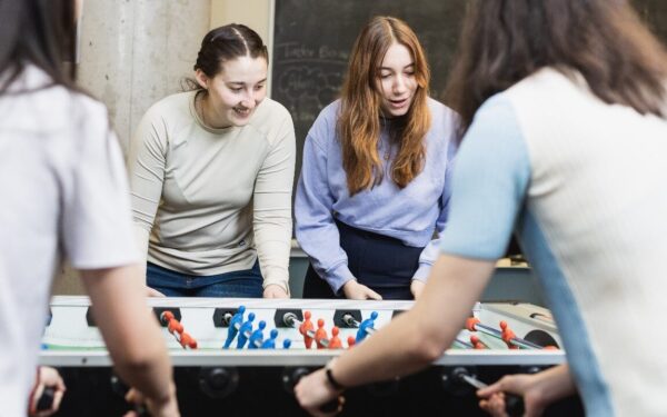 four female students playing a lively game of foosball