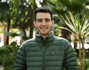 photo of Martin Staadecker wearing a green down jacket outdoors on a sunny day in front of greenery